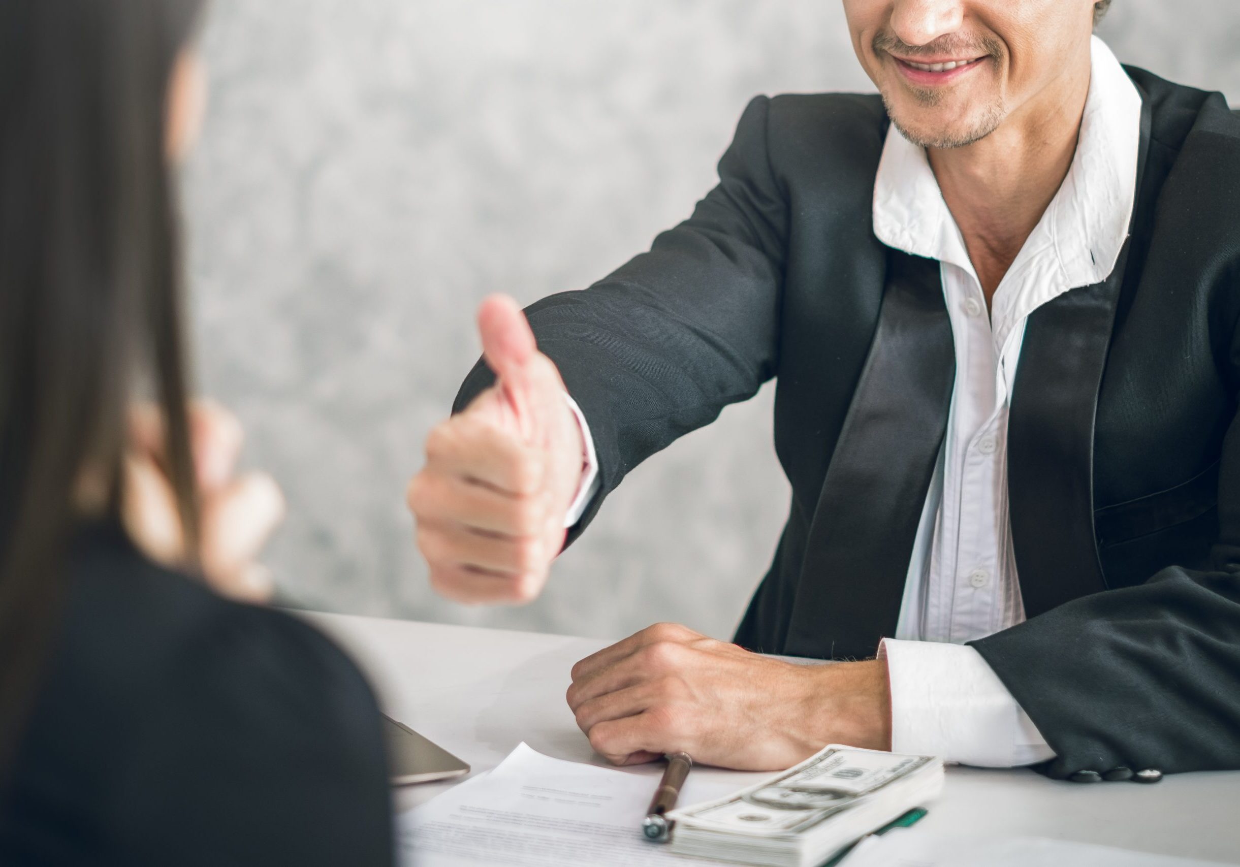 Professional real estate expert giving a thumbs up during a client consultation.