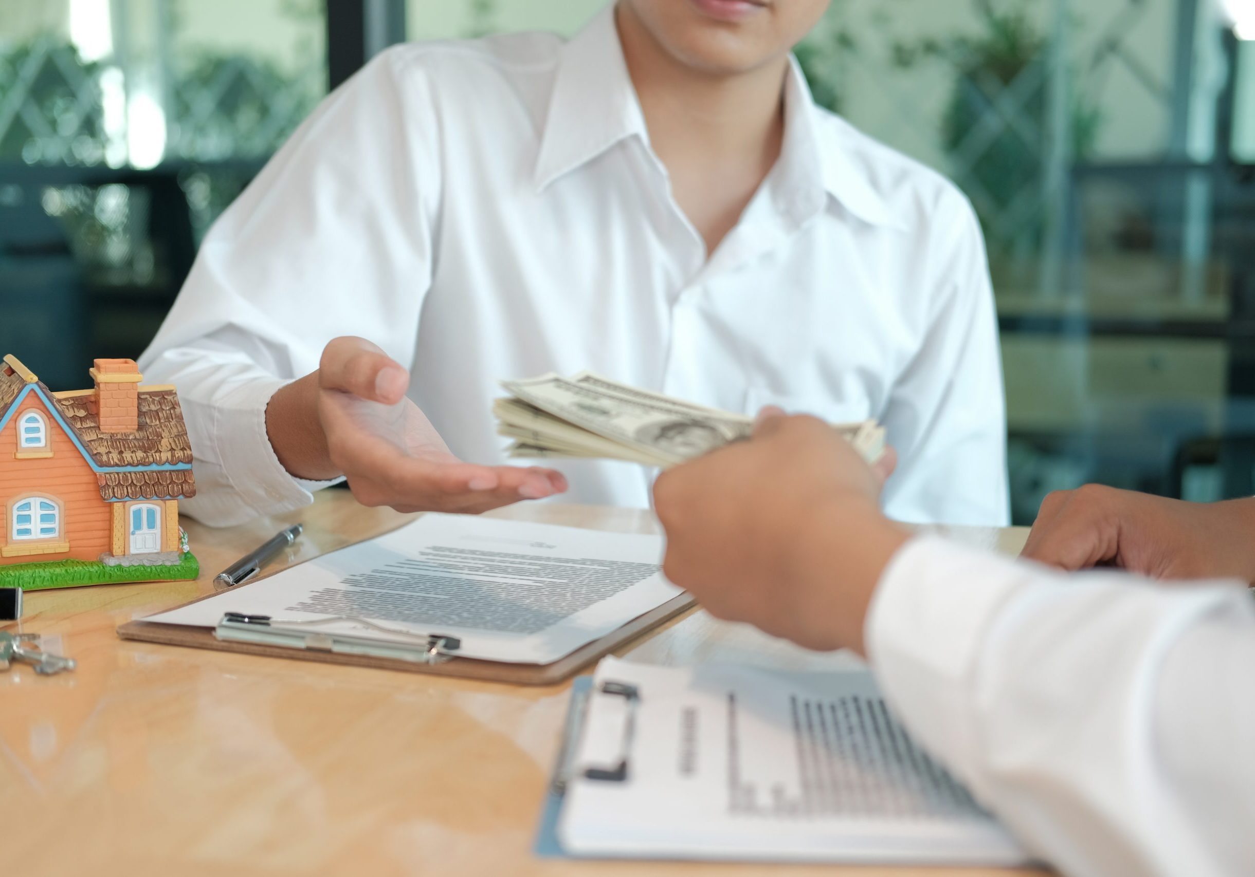 Real estate investor presenting an offer document to a client across a table.