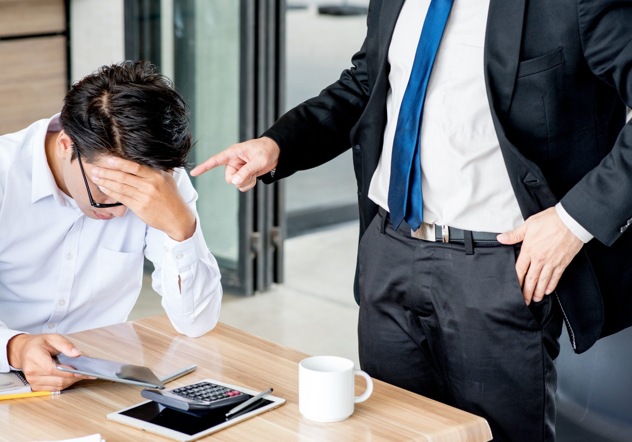 Man at a desk with his head in his hands during a professional meeting about debt.