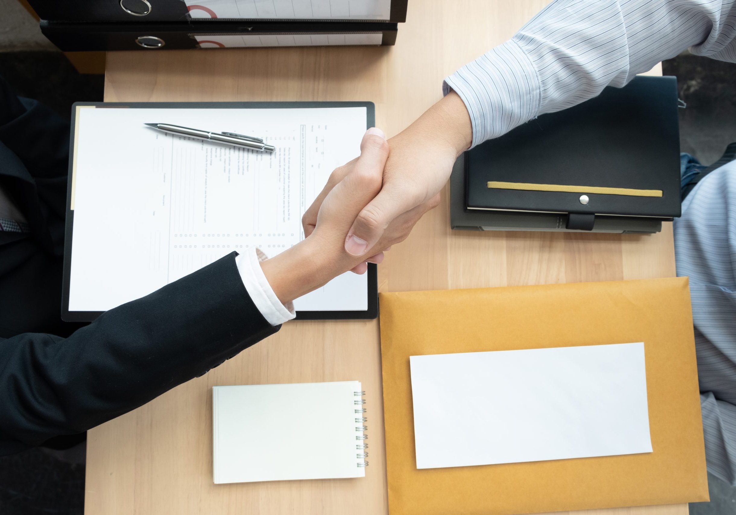 Handshake between two professionals over a signed real estate contract.